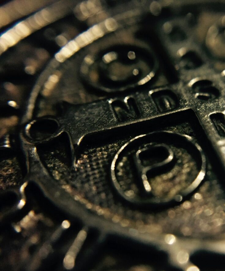 Macro shot of a metallic Saint Benedict medal with intricate religious inscriptions.